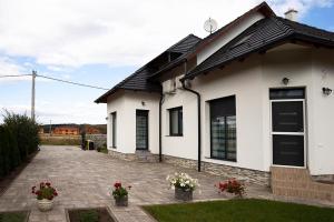 a white house with some flowers in the yard at Győri vendégház in Demjén