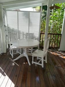 einen weißen Tisch und Stühle auf einer Veranda in der Unterkunft la case dentelle bungalow in Le Diamant