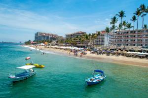 two boats in the water next to a beach at Amapas Apartments Puerto Vallarta in Puerto Vallarta