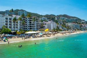 a beach with people in the water and buildings at Amapas Apartments Puerto Vallarta in Puerto Vallarta