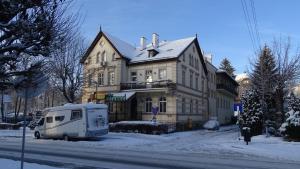 un camion blanc garé devant un bâtiment dans la neige dans l'établissement Willa Zuzanna, à Kudowa-Zdrój