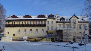 un grand bâtiment jaune avec de la neige devant lui dans l'établissement Willa Zuzanna, à Kudowa-Zdrój