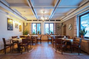 un comedor con mesas, sillas y ventanas en Hotel Aquamarin, en Bad Mitterndorf