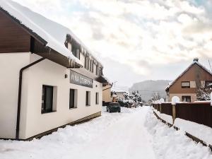 une rue recouverte de neige à côté d'un bâtiment dans l'établissement Apartmány Na Čtvrtích, à Dolní Bečva