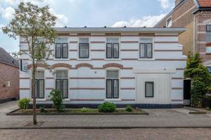 un bâtiment blanc avec un arbre devant lui dans l'établissement Hotel Randenbroek, à Amersfoort