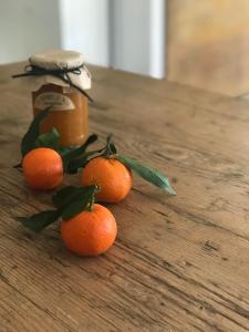 vier sinaasappels op een tafel met een pot honing bij Hotel Les Chambres de Mila in Bonifacio