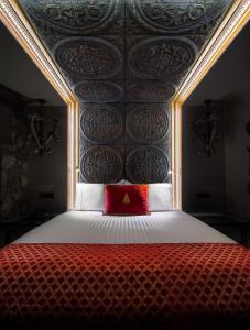 een slaapkamer met een bed met een rood kussen bij KAMARES Historic Boutique Hotel & Spa in Ioannina