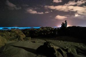 Ein Mann und eine Frau sitzen nachts auf Felsen in der Unterkunft Piedra Alta Hostel & Suites in La Pedrera