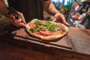 eine Person, die eine Pizza auf einem Schneidebrett hält in der Unterkunft Piedra Alta Hostel & Suites in La Pedrera