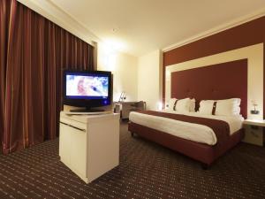 a hotel room with a bed and a flat screen tv at Grand Hotel Mattei in Ravenna