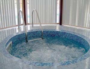 a bath tub with two faucets in a room at Elegant Hotel in Bansko