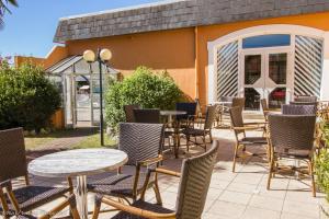 un patio avec des tables et des chaises en face d'un bâtiment dans l'établissement Hôtel Chez Pierre d'Agos, à Agos-Vidalos