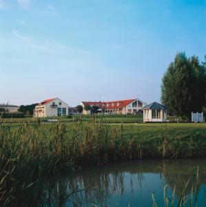 a group of houses in a field next to a lake at Gutshof Sagmühle in Bad Griesbach