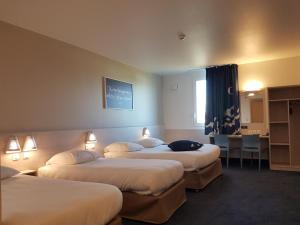 a hotel room with three beds and a desk at Ace Hôtel Toulouse Blagnac in Cornebarrieu