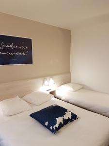 two beds in a room with a sign on the wall at Ace Hôtel Toulouse Blagnac in Cornebarrieu