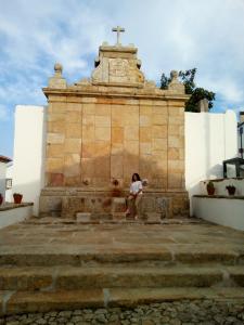 una mujer sentada en una pared junto a un monumento en Quinta Das Lameirinhas, en Marvão