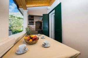 un tavolo con un cesto di frutta sul balcone di Apartments Roko a Duće