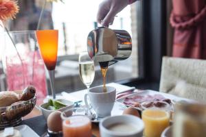 Eine Person schüttet Kaffee in eine Tasse auf einen Tisch. in der Unterkunft Hotel Riant-Séjour by WP Hotels in Blankenberge