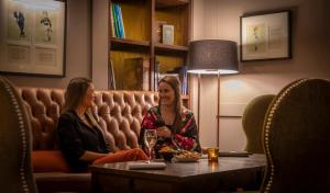 duas mulheres sentadas num sofá num quarto em Clayton Hotel Burlington Road em Dublin