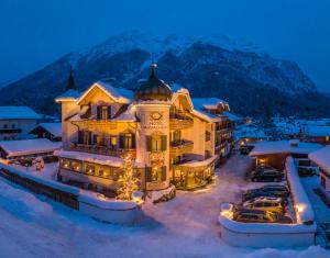 un hotel en la nieve frente a una montaña en Hotel Staudacherhof History & Lifestyle, en Garmisch-Partenkirchen