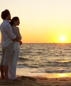 Una coppia in piedi sulla spiaggia a guardare il tramonto di Casa Isabella a Pola (Pula)