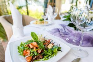 uma mesa branca com um prato de comida e taças de vinho em Hotel La Siesta & Medical Spa em Jastrzębia Góra