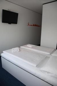 two beds in a room with a tv on the wall at HB1 Budget Hotel - contactless check in in Wiener Neudorf