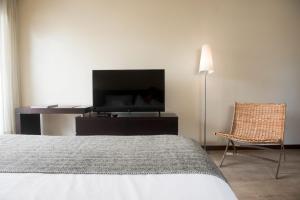 una camera con letto, TV e sedia di 27 Suites Hotel a Montevideo