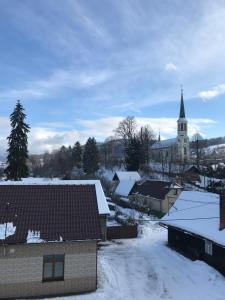 een dorp bedekt met sneeuw met een kerk op de achtergrond bij Ubytování U Valašských ponožek in Hovězí