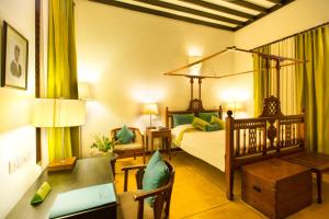 um quarto com uma cama e uma secretária e uma cama sidx sidx em Maison Perumal Pondicherry - a CGH Earth Experience em Pondicherry