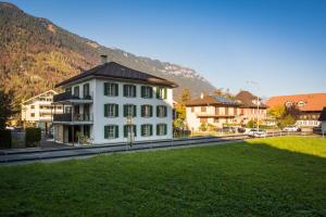 ein weißes Gebäude mit einem schwarzen Dach auf einem grünen Feld in der Unterkunft Dependance First in Interlaken