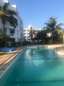 a large swimming pool with palm trees and buildings at Almasi Oceanfront Nyali in Mombasa