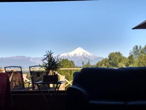 uma vista para uma montanha coberta de neve a partir de uma sala de estar em Cabaña Caburgua Hermosa vista al Volcán, Senderos del Bosque em Pucón