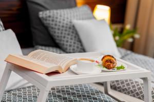 un livre, une tasse de café et une assiette de nourriture sur une table dans l'établissement Apartamenty Black&White, à Gdynia