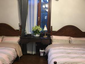 Cette chambre comprend 2 lits et une table fleurie. dans l'établissement Nordic Memory in Qingdao, à Qingdao