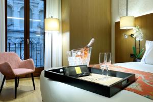 une chambre d'hôtel avec un lit et une table avec une bouteille et des verres dans l'établissement Áurea Catedral by Eurostars Hotel Company, à Grenade