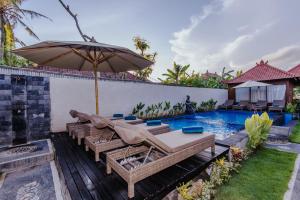 um pátio com um guarda-sol e uma piscina em Lembongan Small Heaven Bungalow em Nusa Lembongan