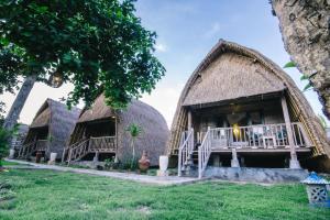 2 cabañas con techo de paja en un campo con árboles en Dream Beach Huts, en Nusa Lembongan