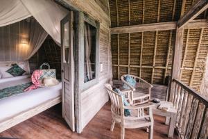 Habitación con balcón, cama y silla. en Dream Beach Huts, en Nusa Lembongan