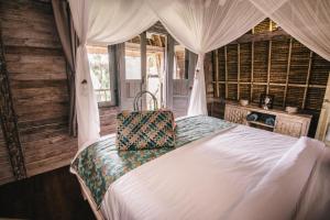 1 dormitorio con 1 cama blanca con dosel en Dream Beach Huts, en Nusa Lembongan