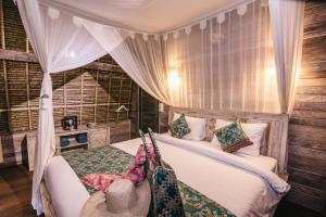 1 dormitorio con 1 cama con dosel en Dream Beach Huts, en Nusa Lembongan