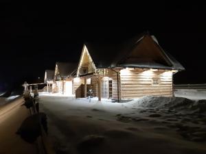 ein Blockhaus leuchtet nachts im Schnee in der Unterkunft Domki Pasja II 2,5 km do wyciągu naciarskiego Czorsztyn Ski in Kluszkowce