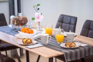 a wooden table with plates of food and glasses of orange juice at Apartments Bakota in Omiš