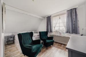 a room with two green chairs and a bed at Landhotel Villa Foresta in Braunlage