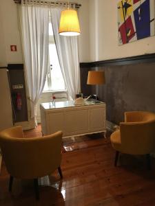 een woonkamer met een tafel en stoelen en een raam bij Hotel Jardim in Coimbra