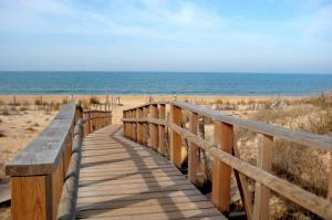 een houten promenade die naar het strand leidt bij Leo Punta Umbría in Punta Umbría