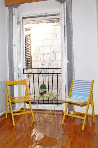 Hostel Korcula في كورتْشولا: كرسيين وطاولة على شرفة مع نافذة