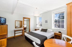 een slaapkamer met een bed, een tafel en een televisie bij Seacombe House Motor Inn Port Fairy in Port Fairy