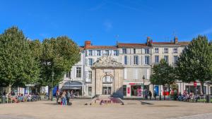 un grand bâtiment blanc avec une fontaine devant lui dans l'établissement ROCHEFORT authentique, à Rochefort