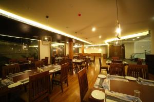 une salle à manger avec des tables et des chaises dans un restaurant dans l'établissement Woodies Bleisure Hotel, à Kozhikode